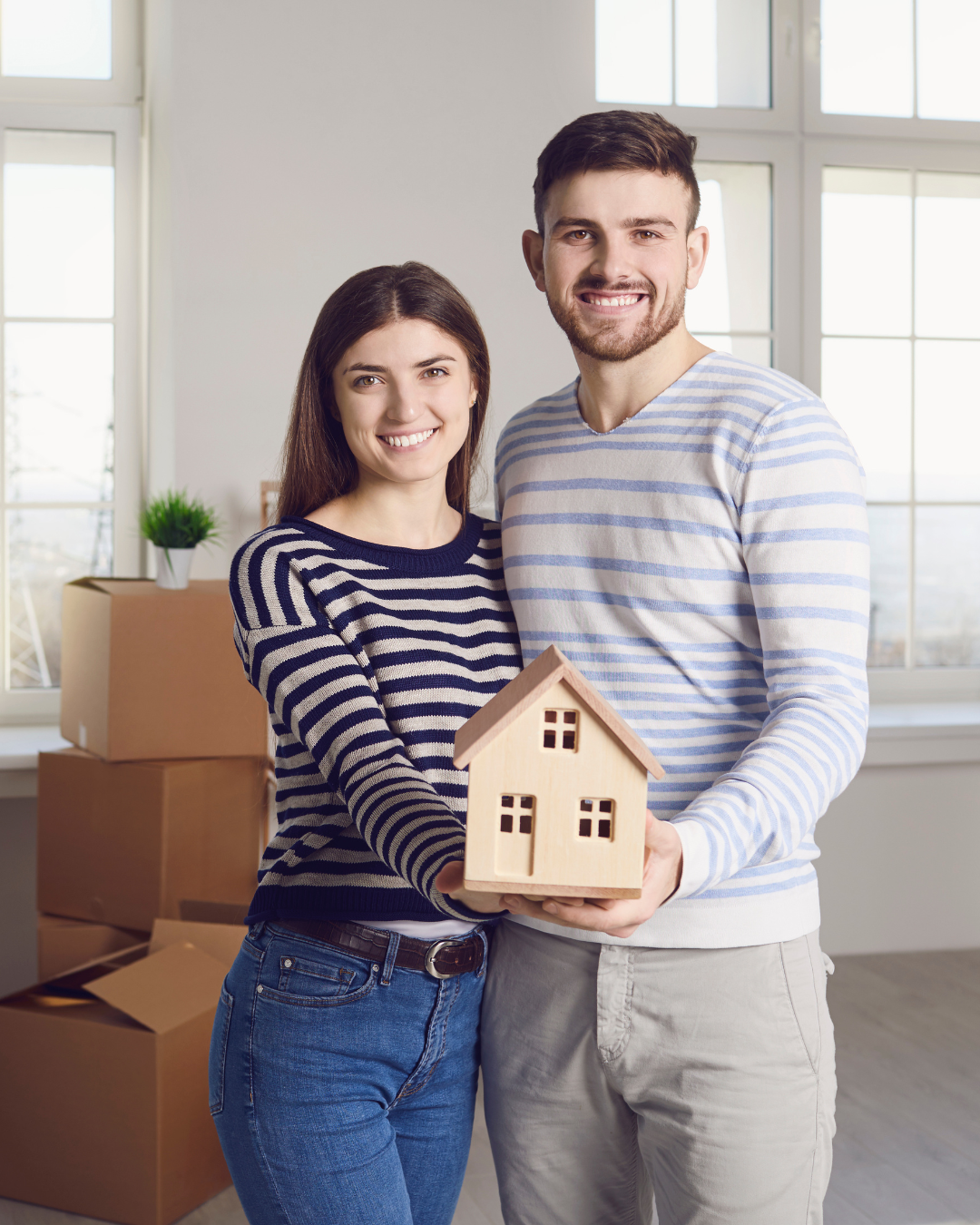 Pareja joven mostrando maqueta de casa tras cumplir con los requisitos del seguro de impago de alquiler