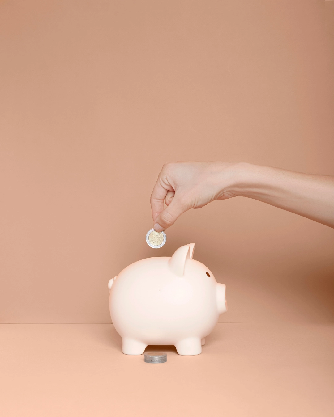 Moneda entrando en una hucha de cerdito como ejemplo práctico de cómo ahorrar siendo joven.