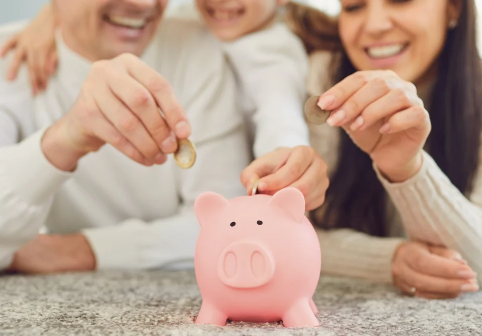 Familia enseñando a sus hijos cómo ahorrar siendo joven con una hucha de cerdito