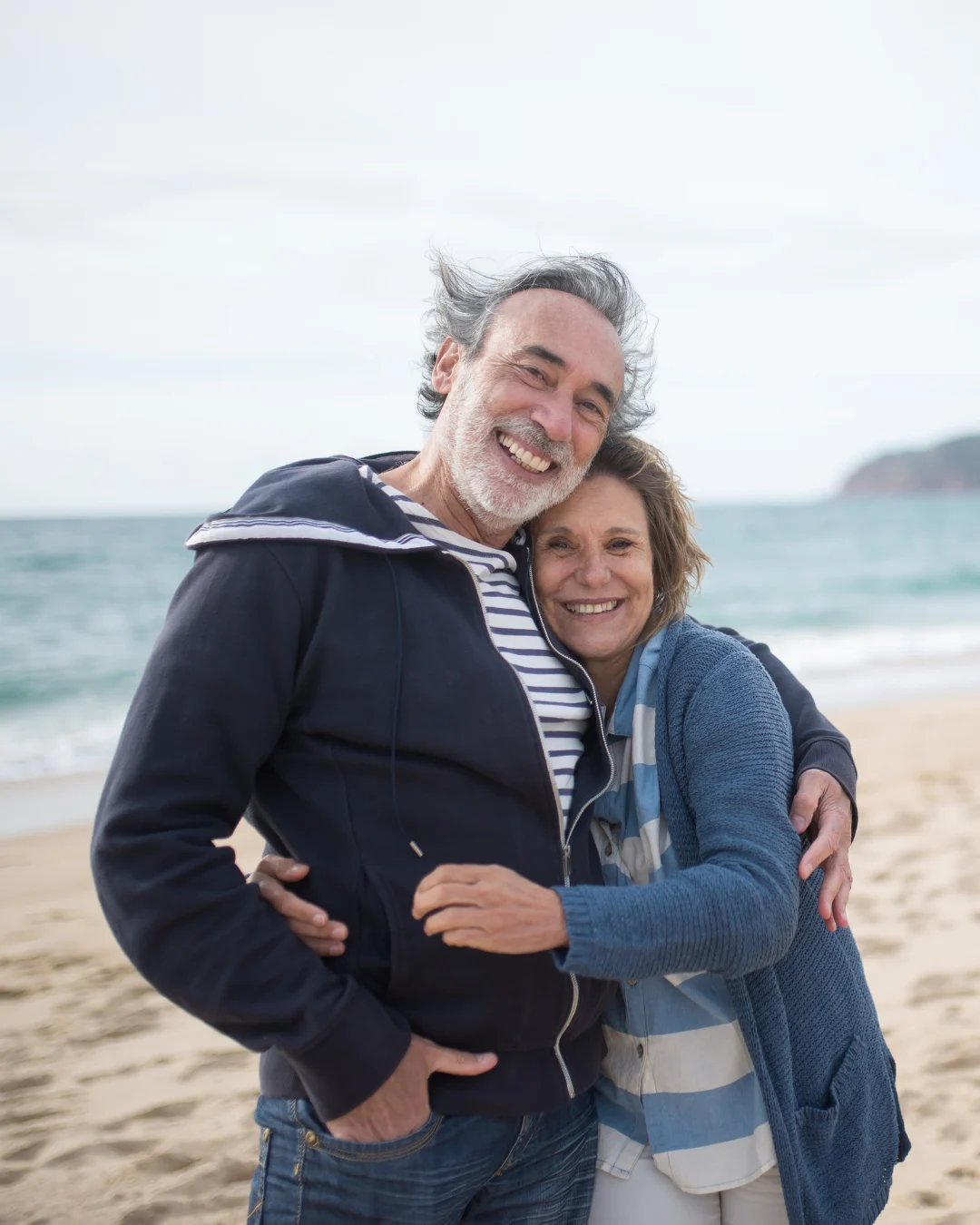 Pareja feliz disfrutando de su jubilación en la playa mientras se informan sobre cuánto cuesta un seguro de decesos para estar tranquilos.