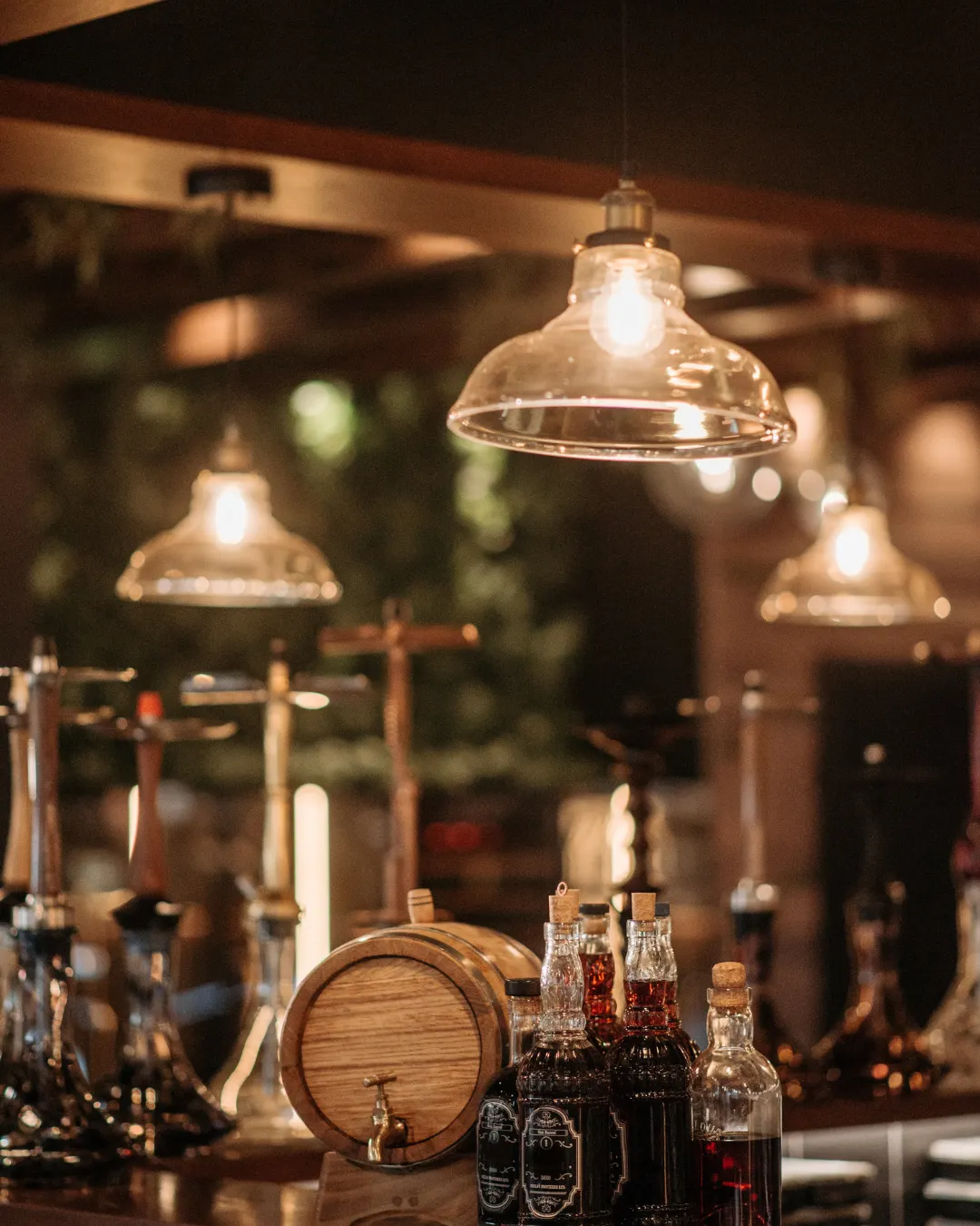 Interior de un local con botellas y barril de madera iluminado, imagen representativa de la importancia de contar con un seguro para bares.