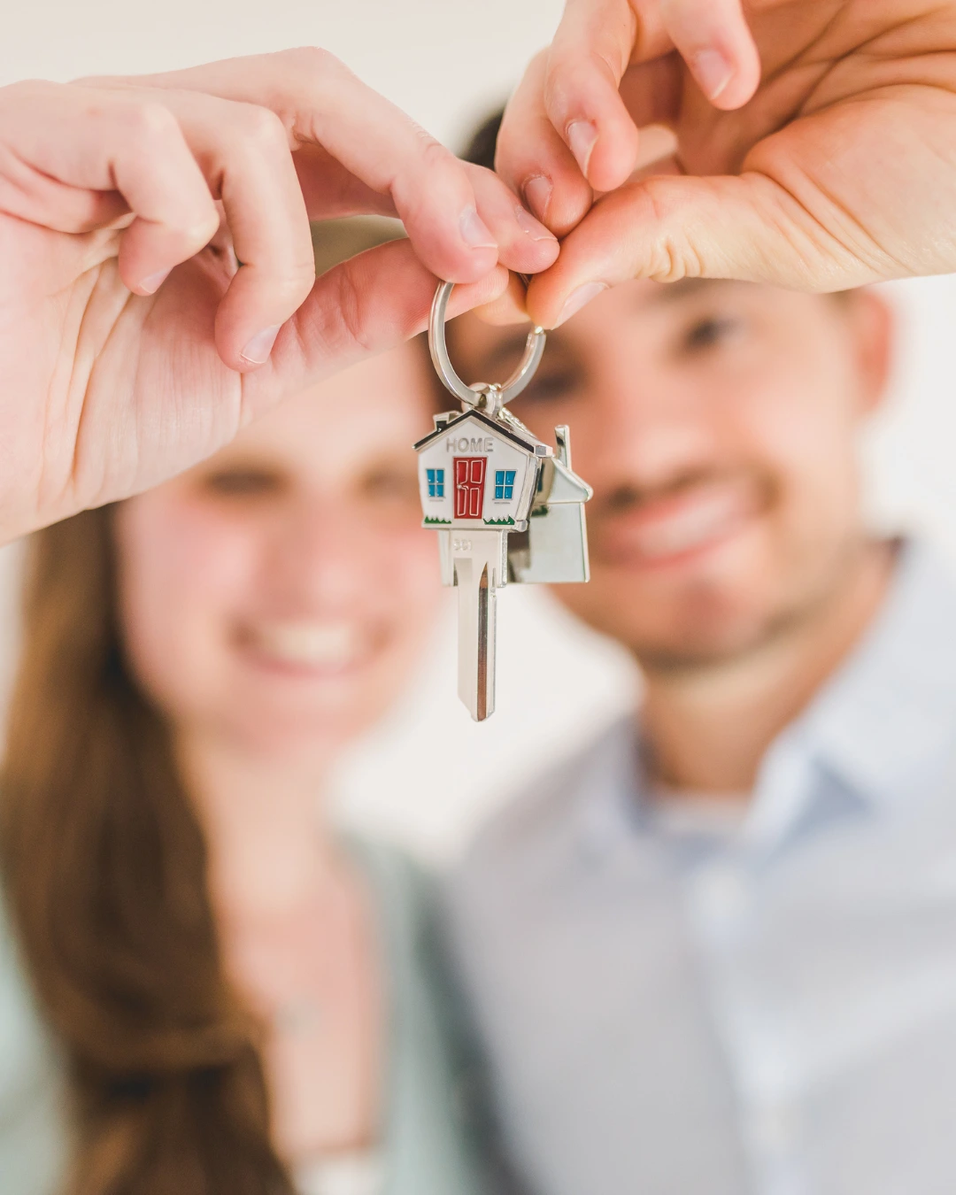 Pareja sosteniendo las llaves de su nuevo hogar, ilustrando las diferencias entre contenido y continente en un seguro de vivienda, que protege tanto la estructura como los bienes personales.