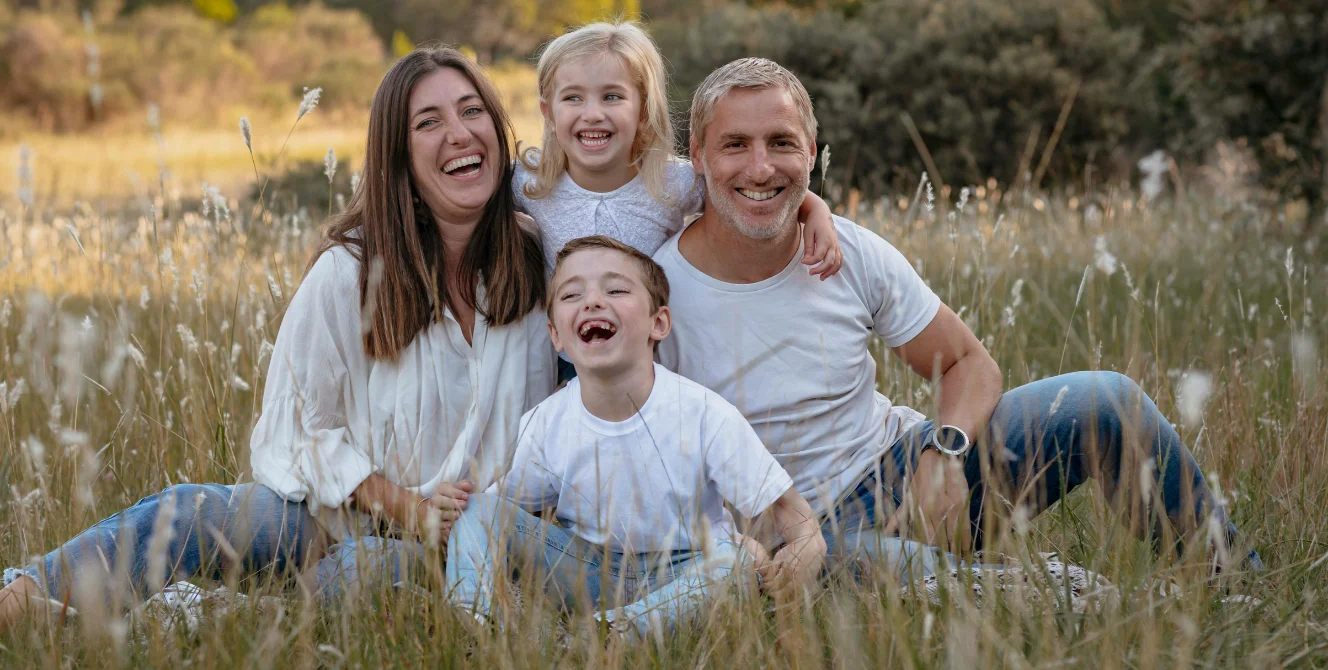 Familia feliz en el campo que representa la diferencia entre contenido y continente en un seguro de hogar, simbolizando el valor de proteger tanto la vivienda como sus bienes.