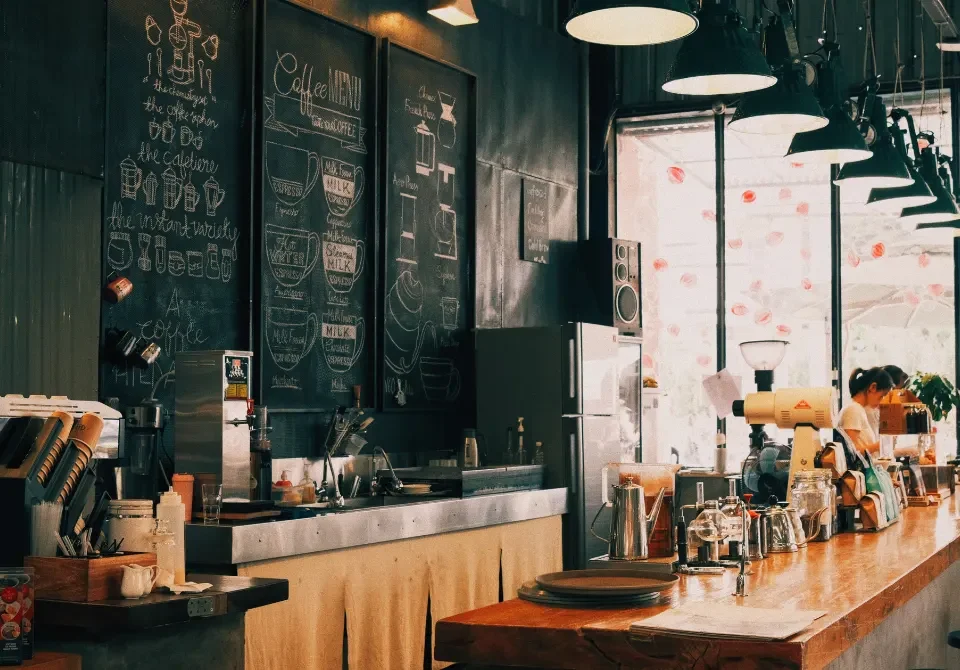 Interior de un bar moderno con barra de madera y baristas preparando café, ideal para ilustrar las coberturas de un seguro para bares.