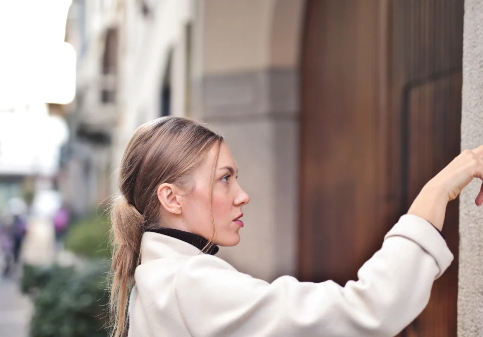 Cubre el seguro de hogar el portero automático: mujer utilizando el portero automático de un edificio residencial
