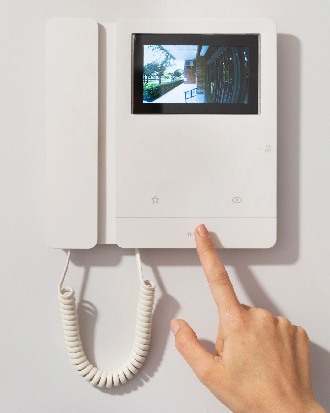 Cubre el seguro de hogar el portero automático: telefonillo privado con pantalla y mano pulsando el botón de apertura