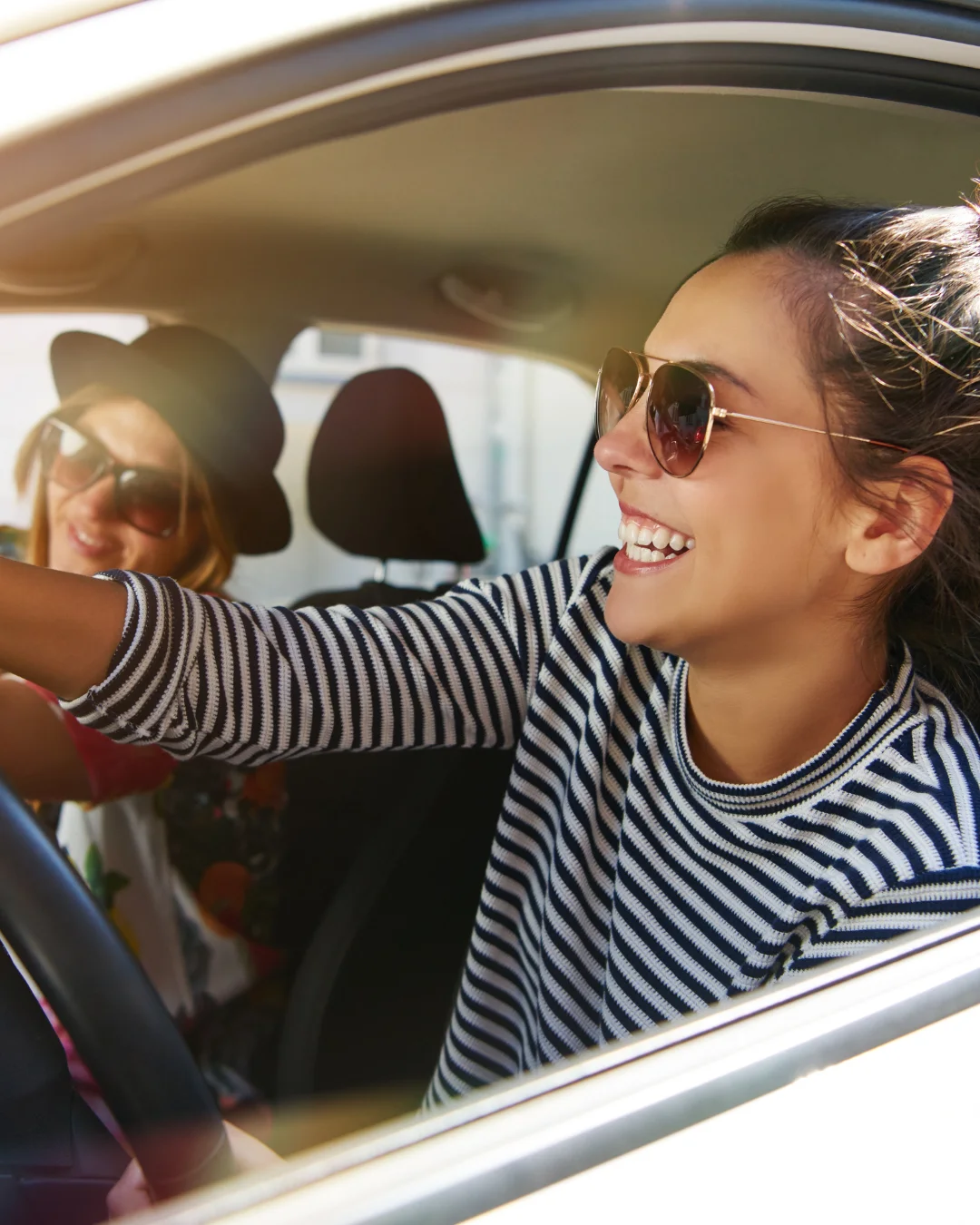 Mujeres felices conduciendo sabiendo lo que significa la franquicia en un seguro.