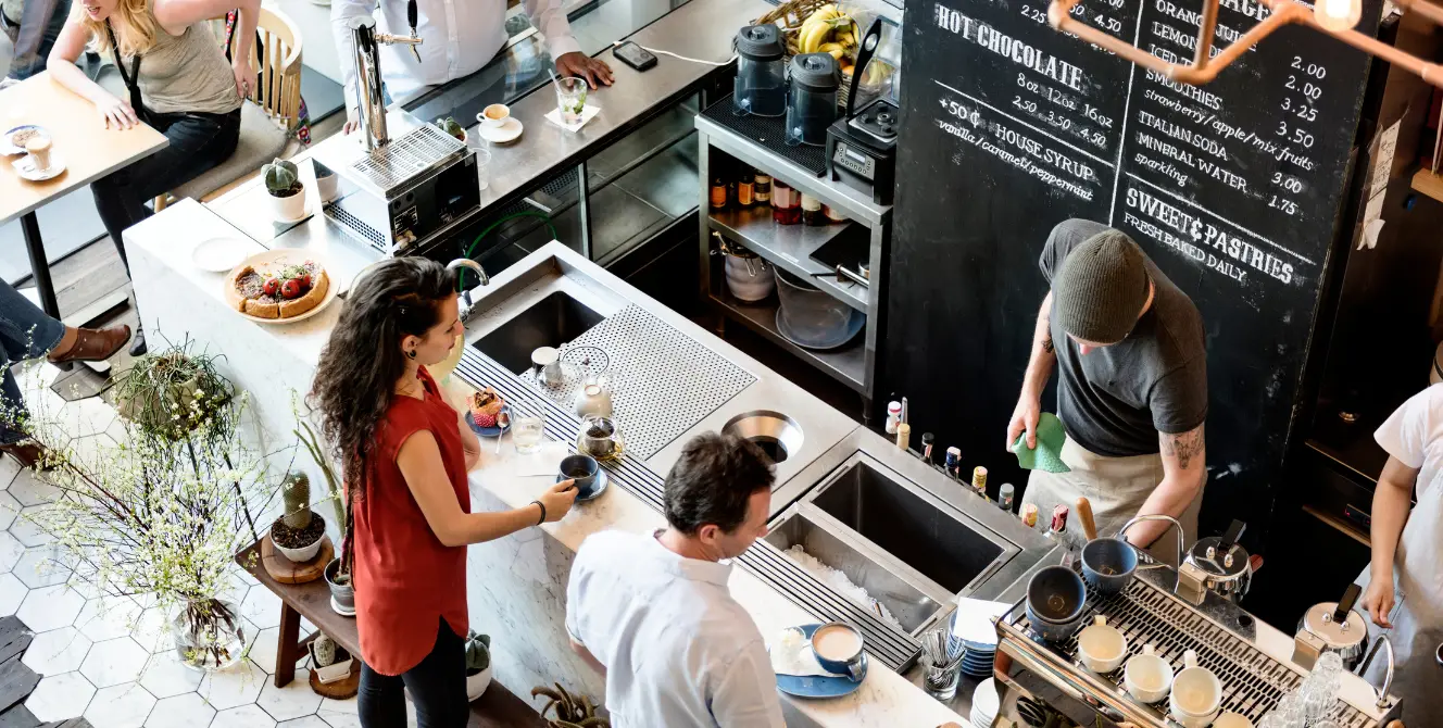 Seguro para local alquilado: interior de una cafetería con clientes y personal trabajando en la barra