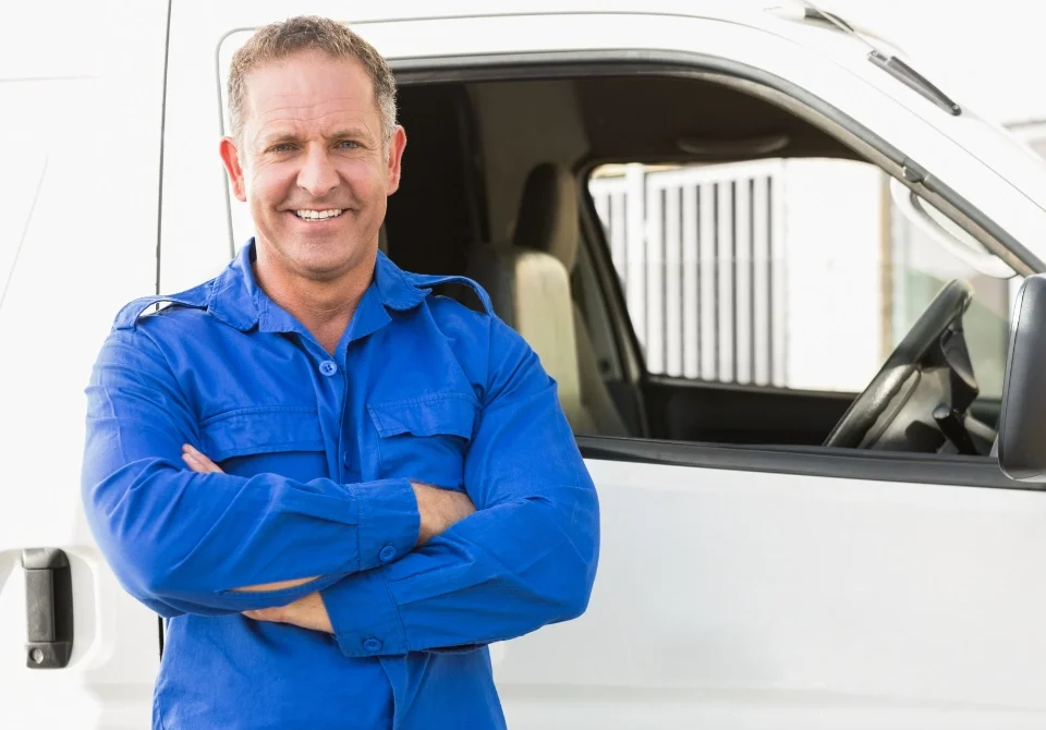 Conductor profesional junto a una furgoneta blanca, imagen para seguros para furgonetas.