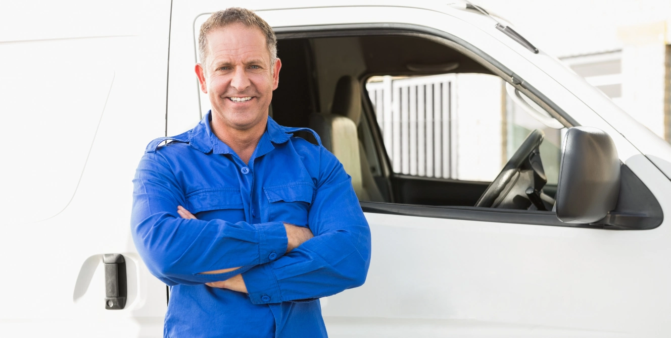 Conductor profesional junto a una furgoneta blanca, imagen para seguros para furgonetas.