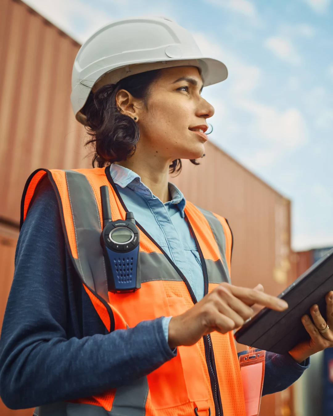 Técnica de seguridad con casco y chaleco reflectante revisando una tablet en zona industrial, relacionada con los tipos de accidentes laborales.