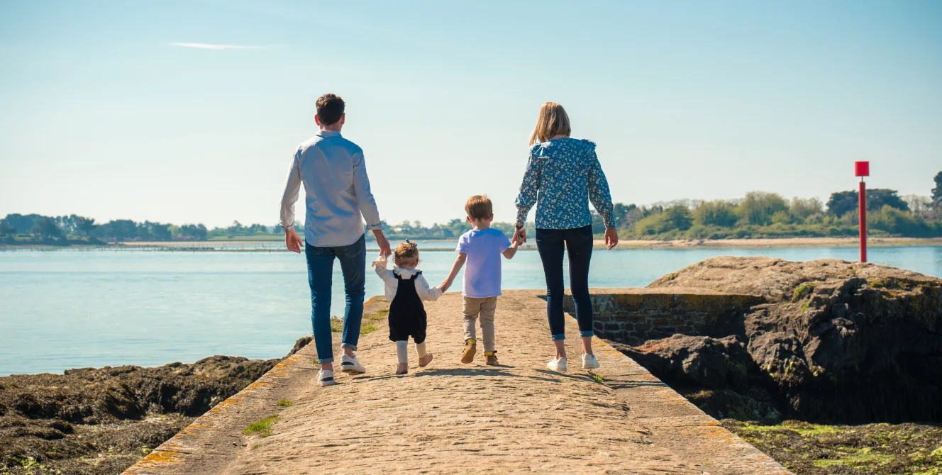 Familia caminando junto al mar representando los tipos de seguros de vida Ges Seguros y la protección familiar