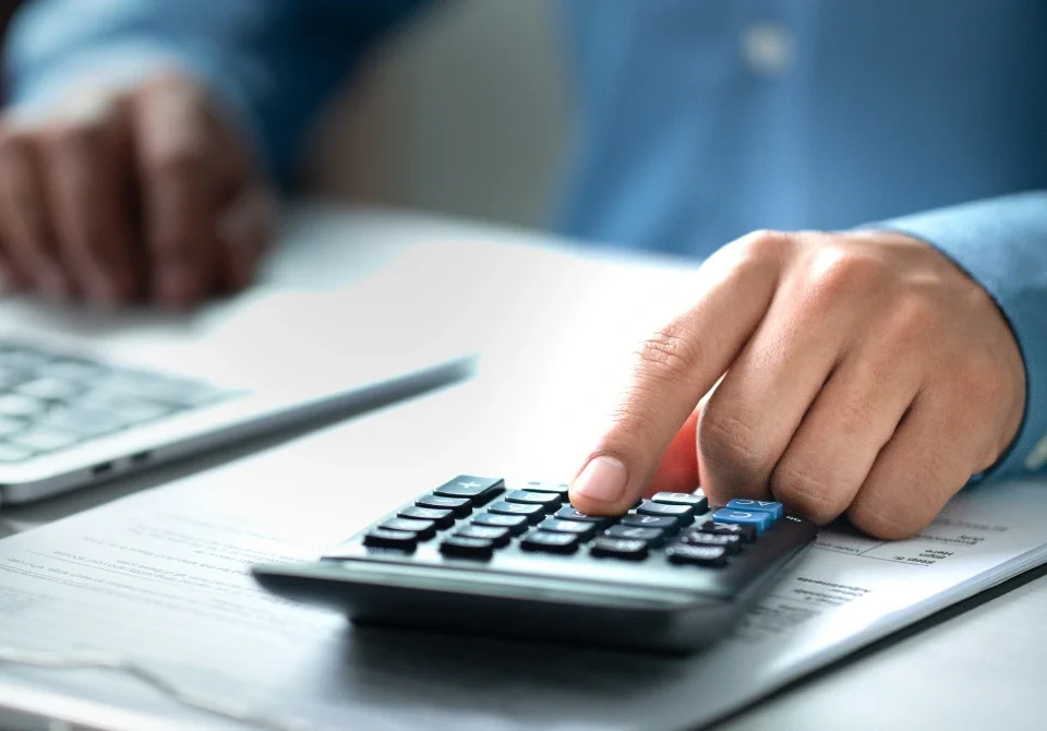 Persona con calculadora y documentos revisando los trámites en el banco después del fallecimiento