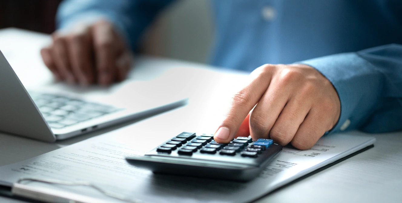 Persona con calculadora y documentos revisando los trámites en el banco después del fallecimiento